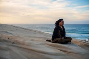 Femme assise sur une dune contemplant l'horizon
